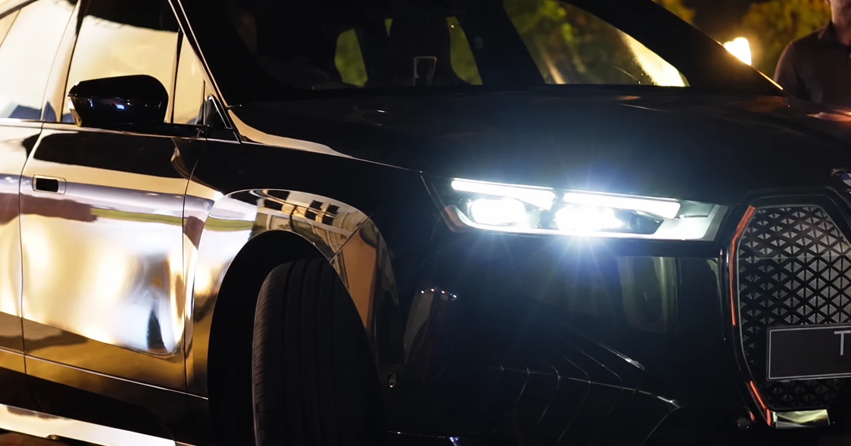 A black BMW with its headlights illuminated at the event