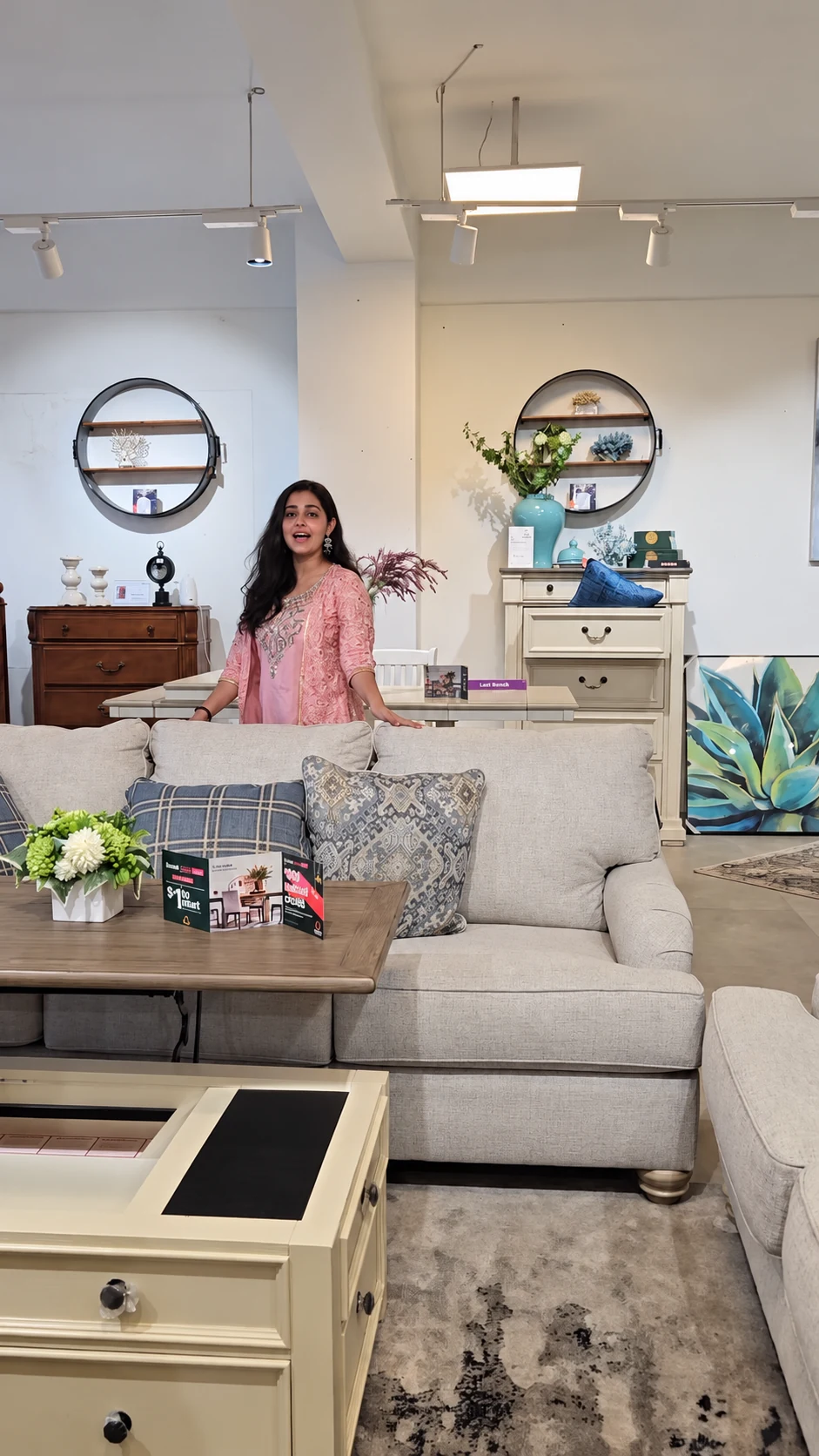 A creator in pink speaking to the camera from behind a cream showroom sofa