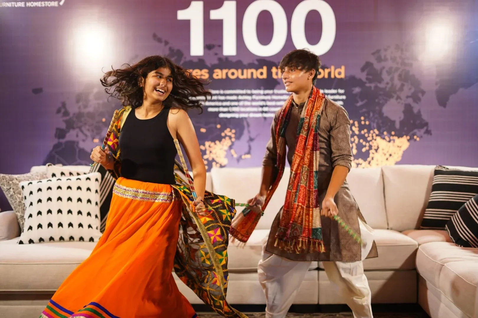 A young woman and man dancing at Garba night beside the Ashley furniture setting
