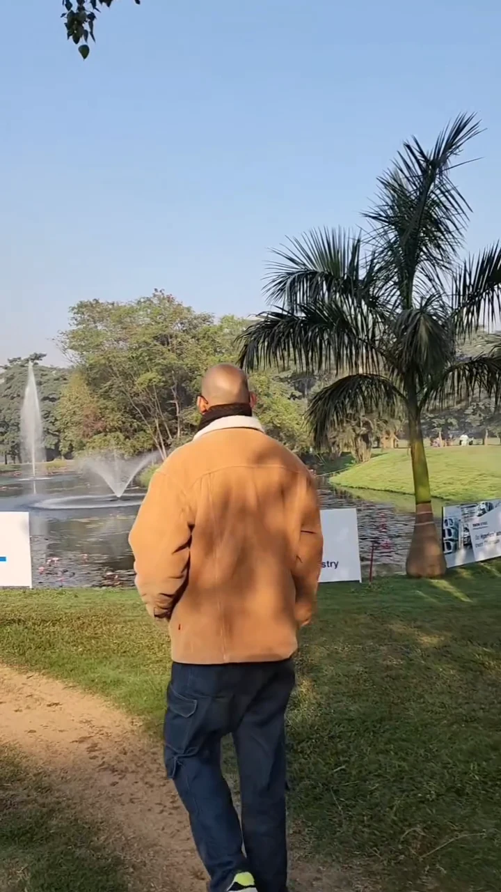 The creator walking beside palms and a fountain at the golf course