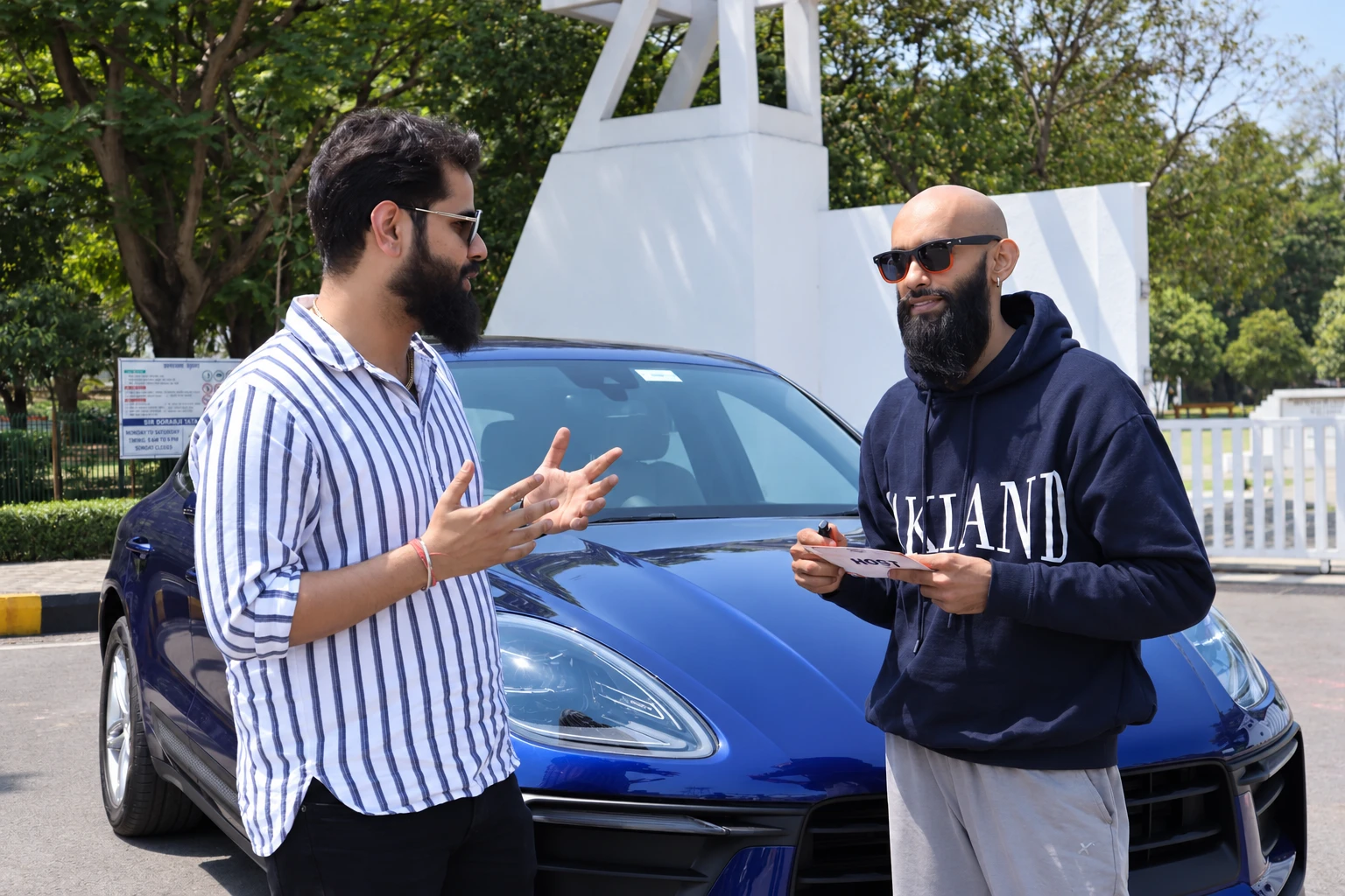 Aditya in conversation beside a Porsche during the Ashley Jamshedpur work