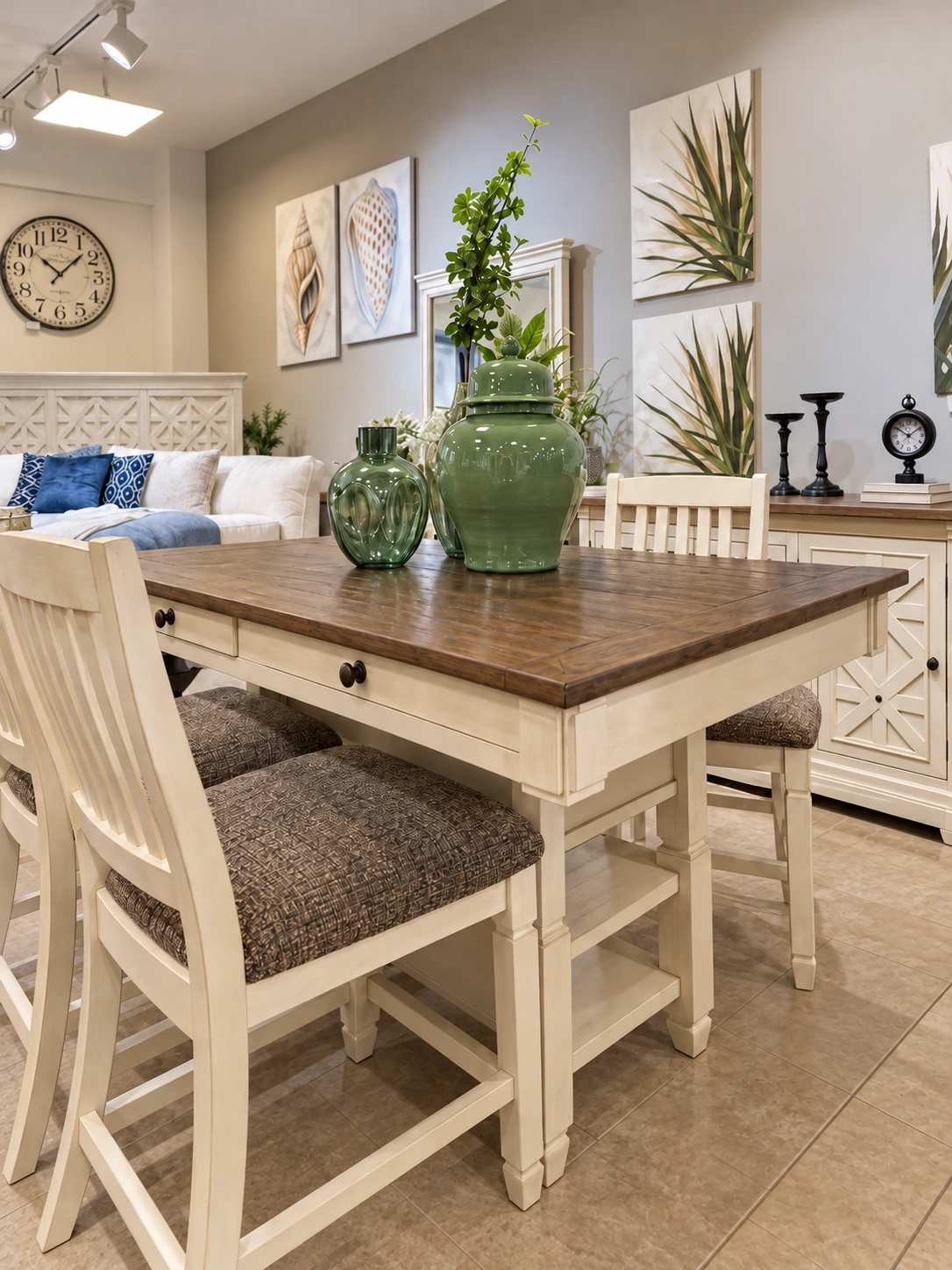 A white and wood dining table, upholstered chairs and green ceramic vessels in the showroom