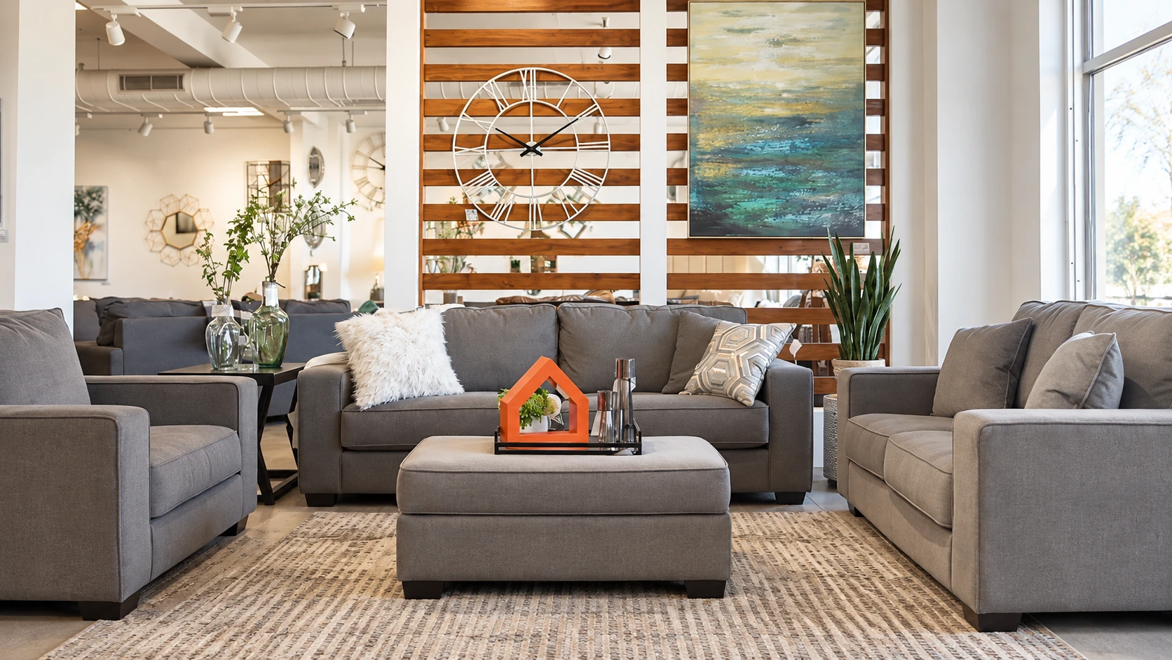 A grey sofa, armchairs and ottoman arranged as a living room inside Ashley’s showroom