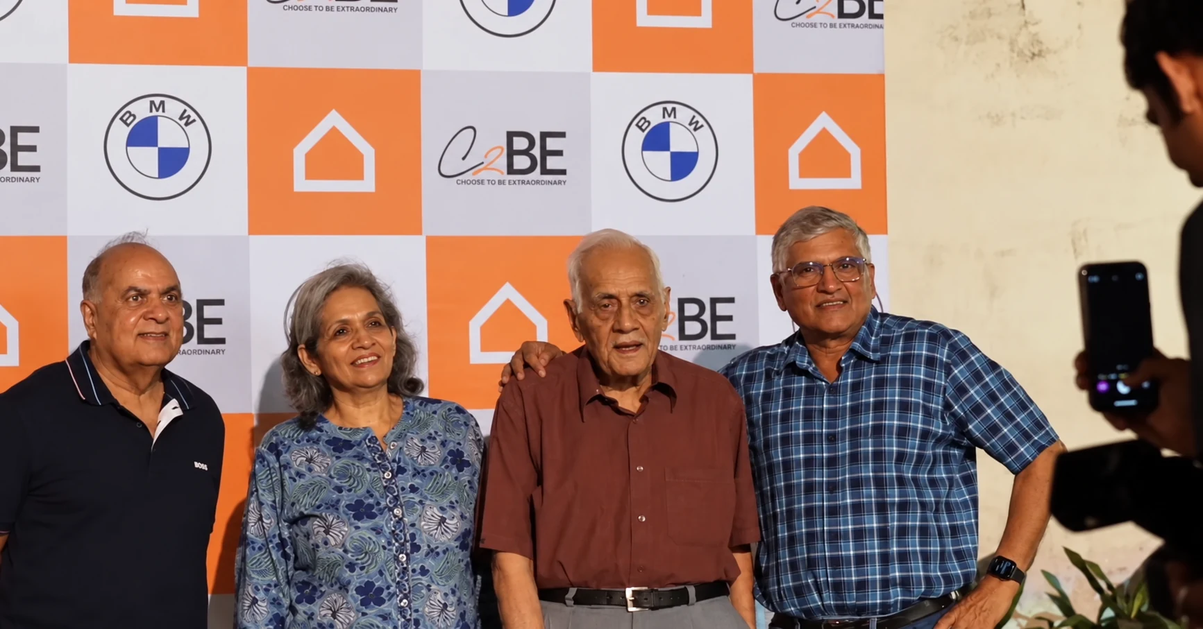 Guests gathered in front of a backdrop repeating the Ashley house mark, BMW emblem and C2BE name