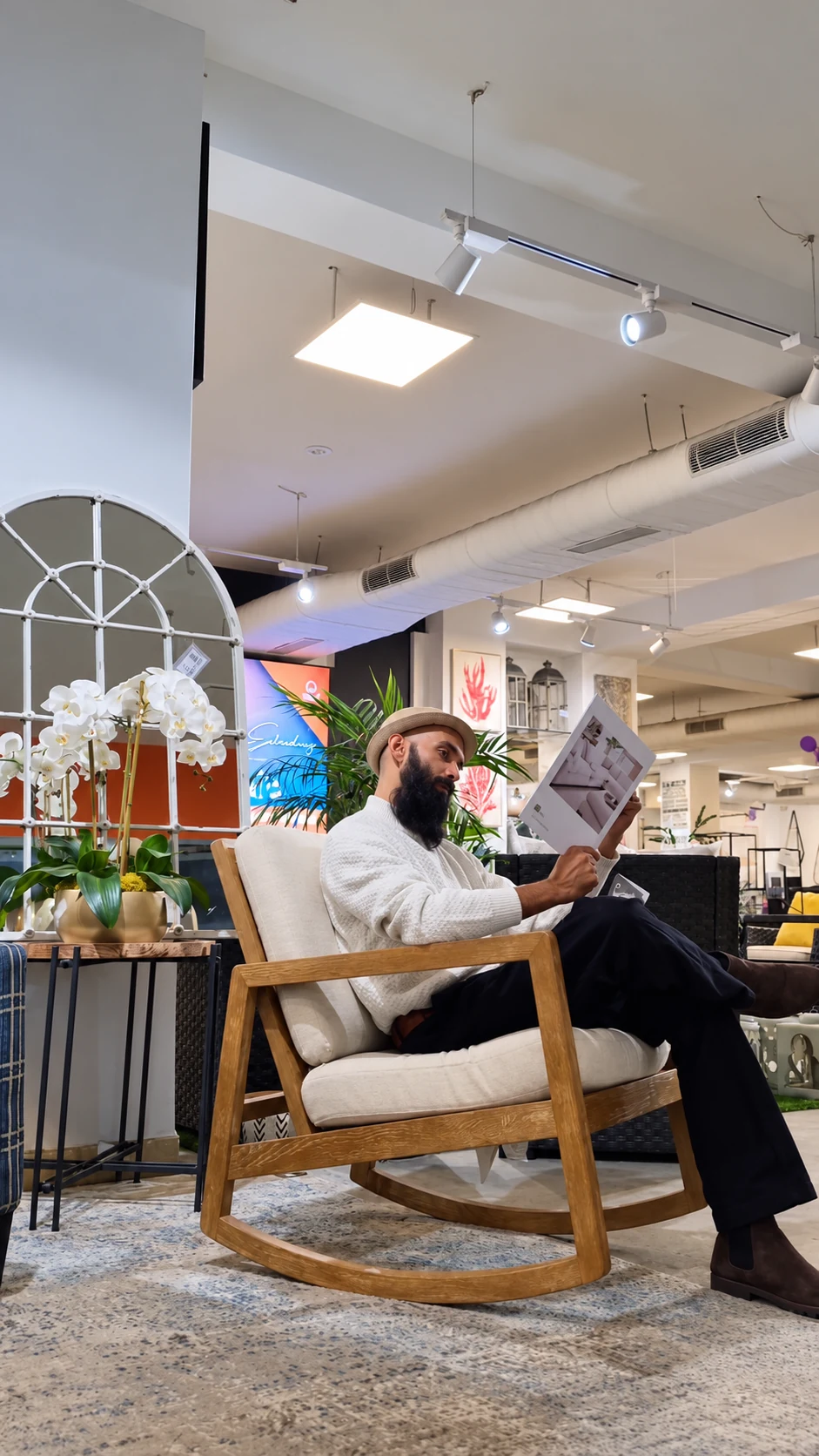 The creator seated in an upholstered wooden armchair, looking at a brochure