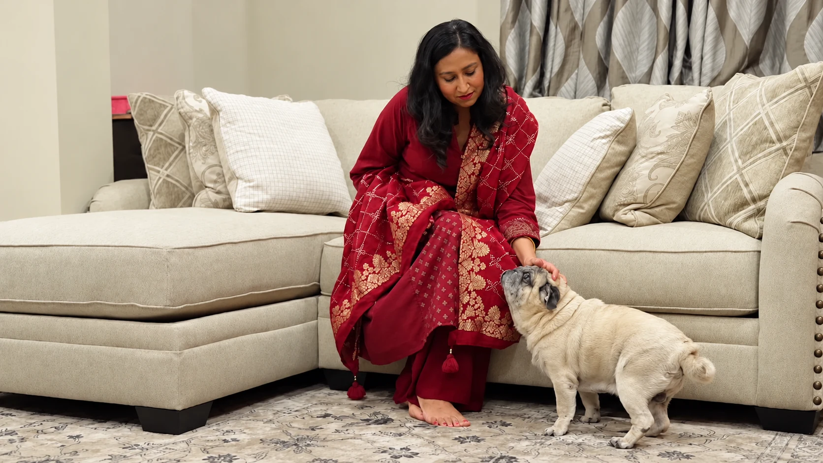 A customer seated on her cream Ashley sectional at home, reaching down to stroke her dog