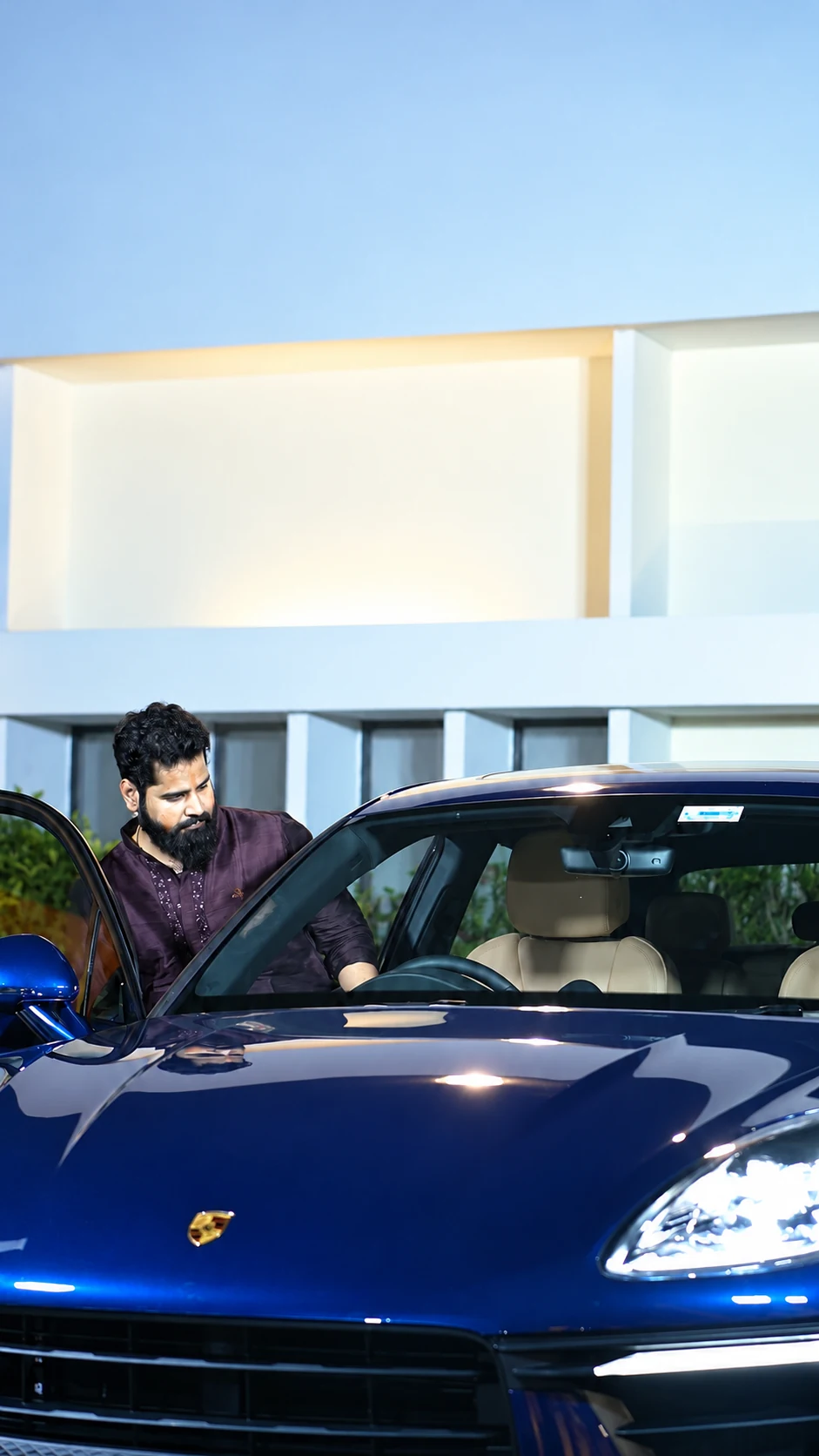 An attendee looking into the blue Porsche through its open door at the Orange Event