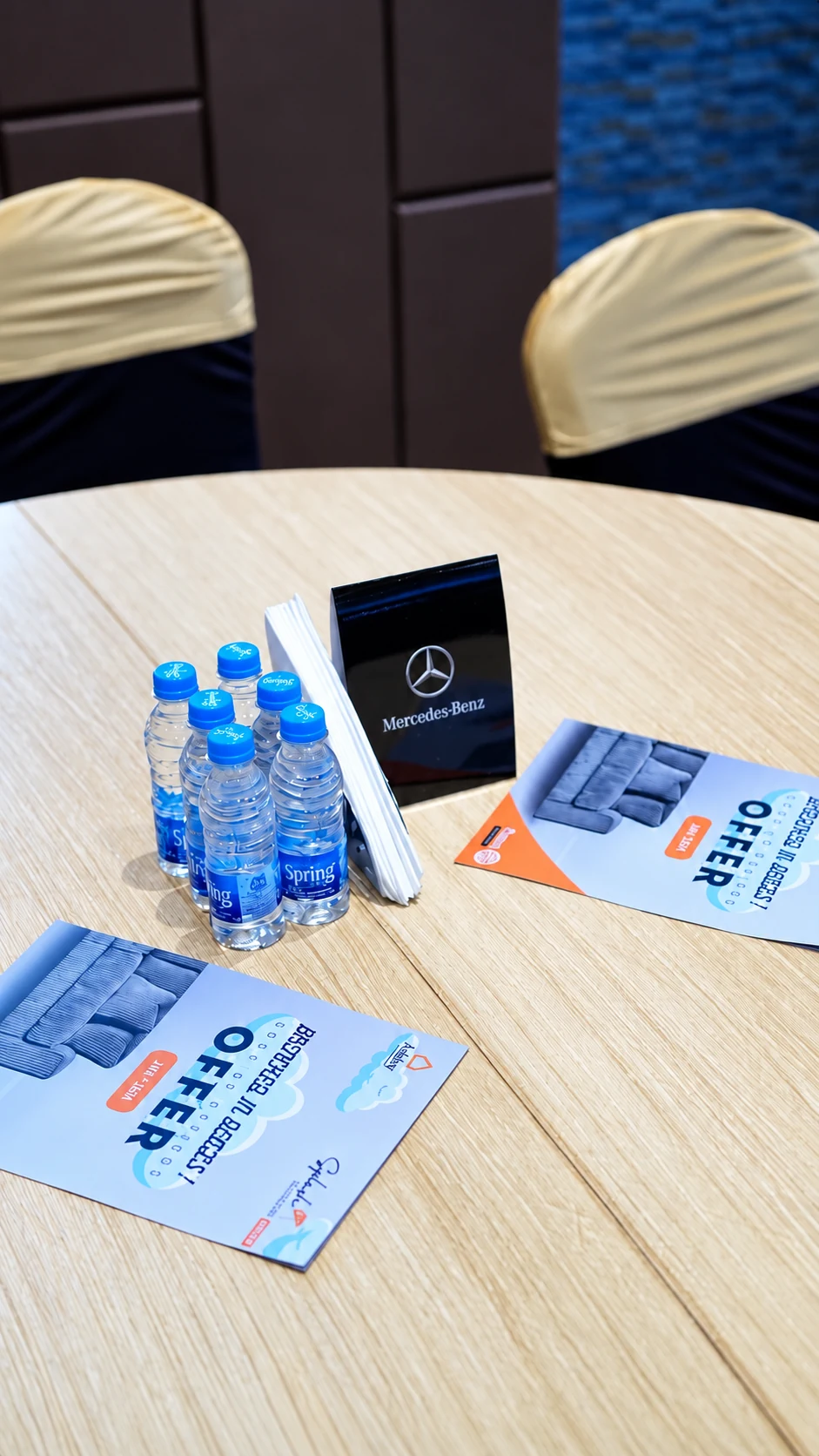 A Mercedes-Benz tabletop display beside Ashley furniture offer brochures at the Rotary awards